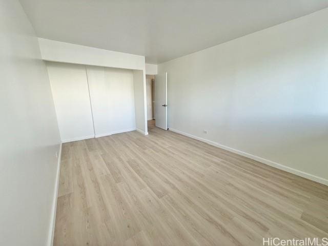 unfurnished bedroom with light wood-type flooring, a closet, and baseboards