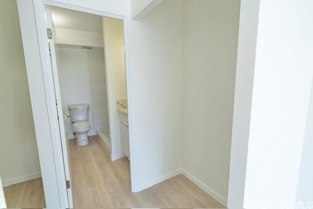 bathroom with toilet, vanity, wood finished floors, and baseboards