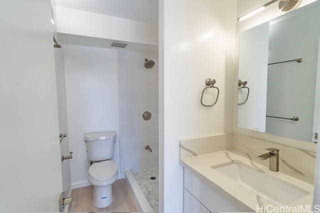 bathroom featuring toilet, vanity, and a stall shower