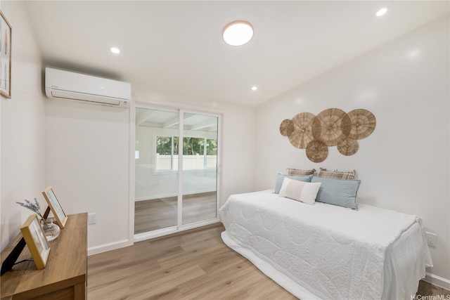 bedroom featuring an AC wall unit, recessed lighting, light wood-style floors, and access to exterior