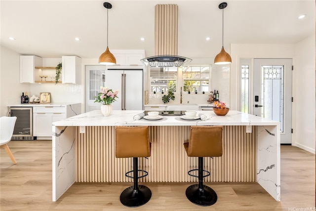 kitchen featuring light wood finished floors, island range hood, open shelves, built in fridge, and beverage cooler