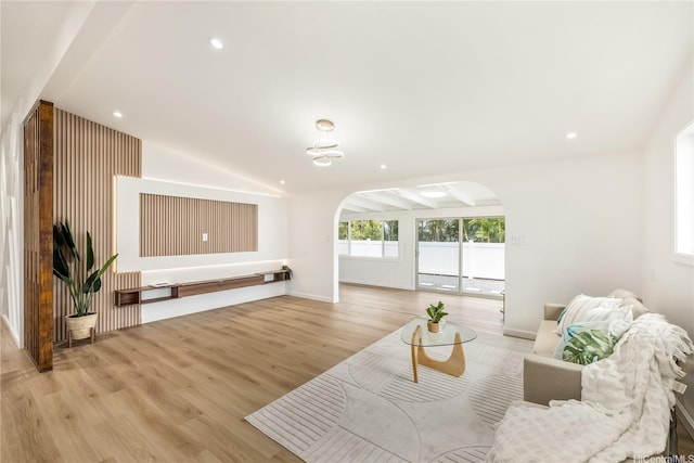 living room with light wood-style flooring, arched walkways, baseboards, recessed lighting, and lofted ceiling