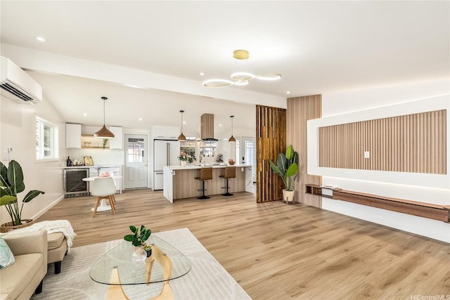 living area featuring light wood finished floors, wine cooler, recessed lighting, a chandelier, and a wall mounted air conditioner