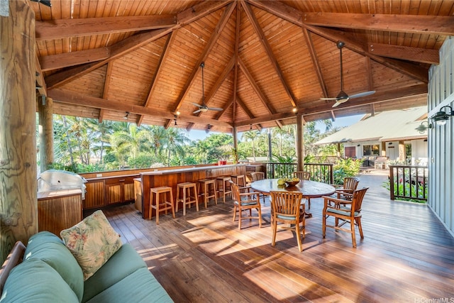 wooden deck featuring grilling area, ceiling fan, a gazebo, and exterior bar