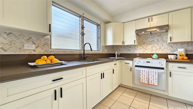kitchen with dark countertops, a sink, under cabinet range hood, and white range with electric stovetop