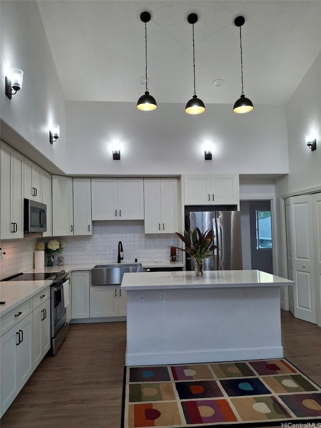 kitchen featuring a center island, a sink, decorative backsplash, stainless steel appliances, and dark wood-style floors