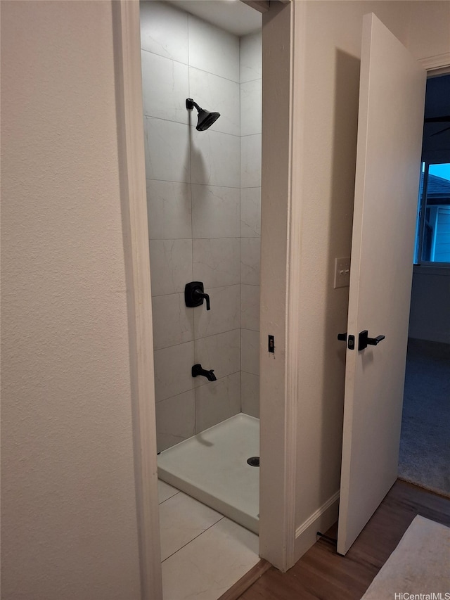 bathroom with baseboards, wood finished floors, and a stall shower
