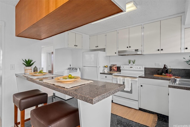 3350 Sierra Dr Unit 601, Honolulu, HI 96816 - kitchen with dark countertops, under cabinet range hood, white appliances, a kitchen bar, and washer / clothes dryer