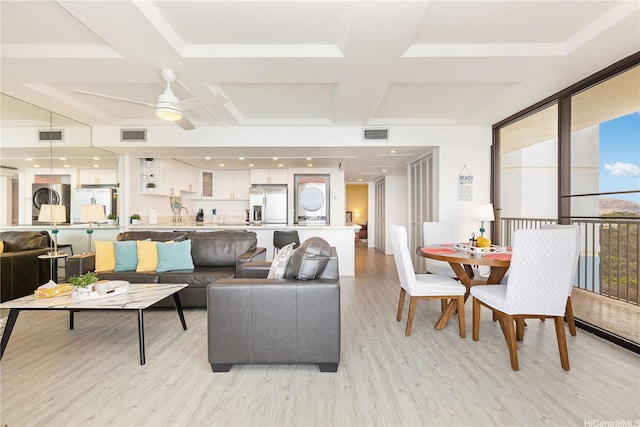 living room featuring coffered ceiling, stacked washer and dryer, visible vents, and light wood-style floors