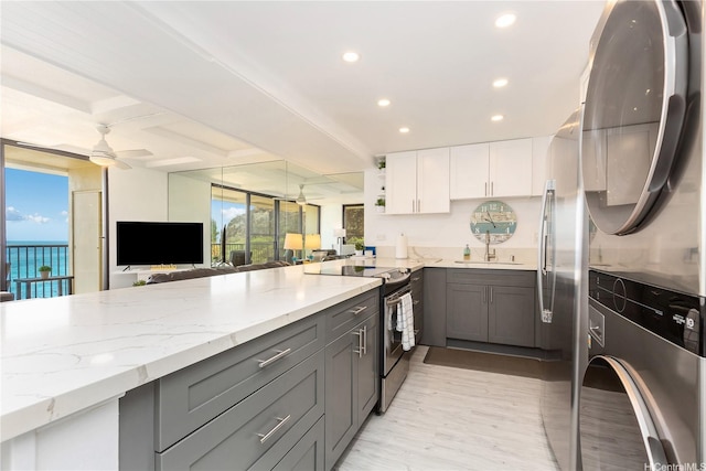 kitchen featuring stacked washer and dryer, stainless steel range with electric cooktop, recessed lighting, light stone counters, and gray cabinets