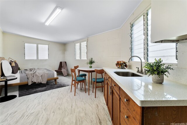 1727 Ema Pl, Honolulu, HI 96819 - kitchen featuring light stone counters, a sink, brown cabinetry, open floor plan, and concrete block wall