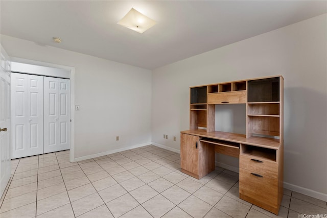 unfurnished office with baseboards and light tile patterned floors