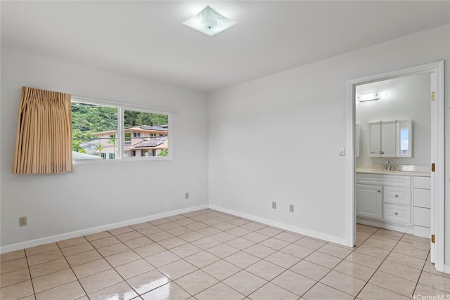 unfurnished bedroom with baseboards, a wall mounted AC, ensuite bath, and light tile patterned flooring