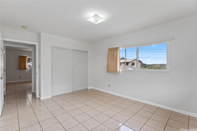 unfurnished bedroom with baseboards, light tile patterned floors, and a closet