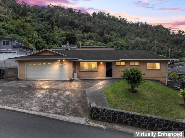 single story home featuring a garage, driveway, a front yard, and a shingled roof