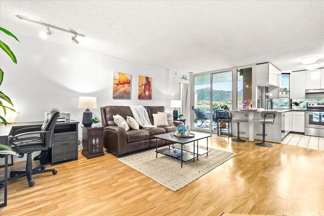 1212 Nuuanu Ave Unit 1306, Honolulu, HI 96817 - living room with a textured ceiling, light wood finished floors, a desk, track lighting, and floor to ceiling windows