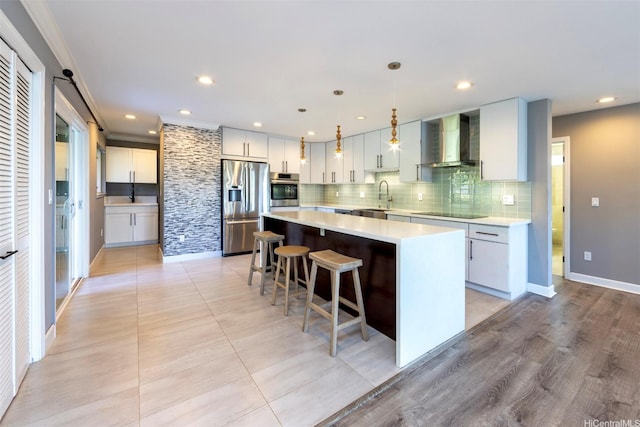 kitchen with backsplash, light countertops, a sink, wall chimney exhaust hood, and appliances with stainless steel finishes