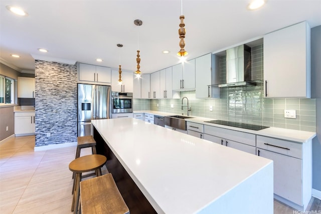 kitchen featuring wall chimney range hood, decorative backsplash, appliances with stainless steel finishes, and a sink