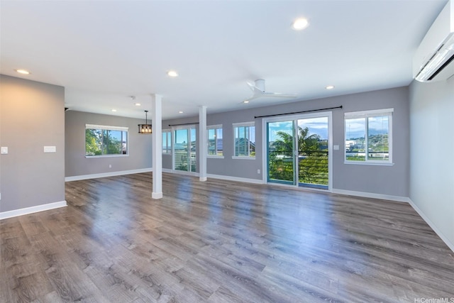 unfurnished living room featuring baseboards, a wall mounted AC, and recessed lighting