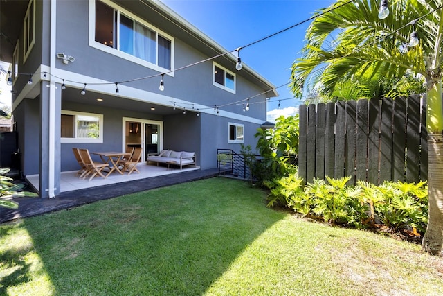 back of property with fence, a patio, a yard, and stucco siding