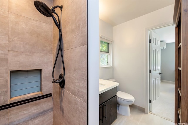bathroom with toilet, vanity, tiled shower, and tile patterned floors