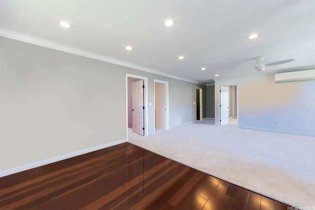 spare room with recessed lighting, a wall unit AC, wood-type flooring, crown molding, and baseboards