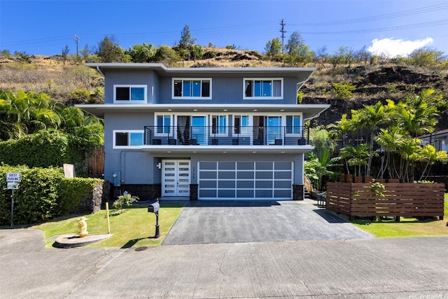 view of front facade with aphalt driveway, stone siding, an attached garage, a balcony, and stucco siding
