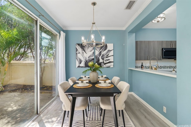 dining area with wood finished floors, a chandelier, and ornamental molding