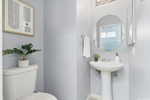 bathroom with toilet, baseboards, and a sink
