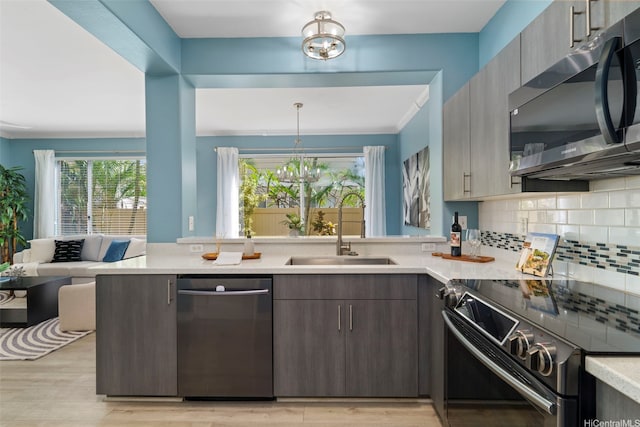 kitchen with a sink, stainless steel appliances, light countertops, backsplash, and a peninsula