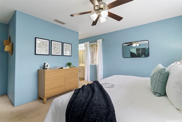 bedroom featuring light colored carpet, ceiling fan, and ensuite bath