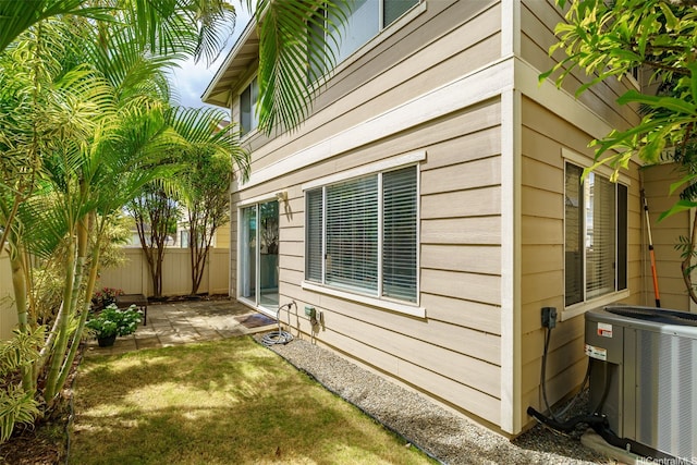 view of home's exterior with central AC, fence, and a patio