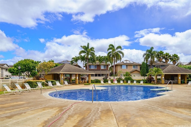 community pool featuring a gazebo, fence, a patio area, and a residential view