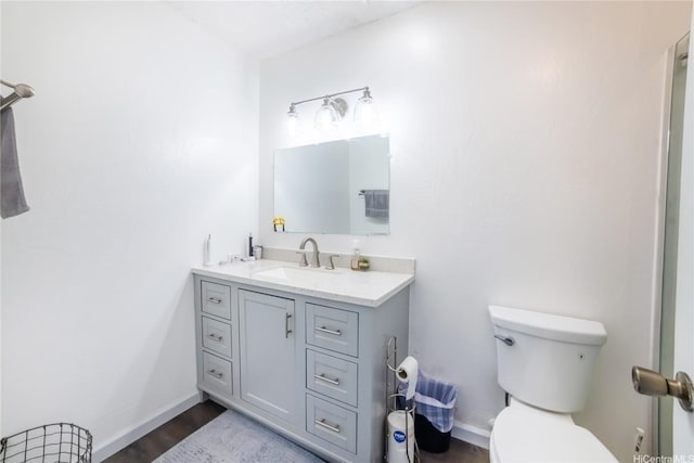 bathroom featuring wood finished floors, vanity, toilet, and baseboards