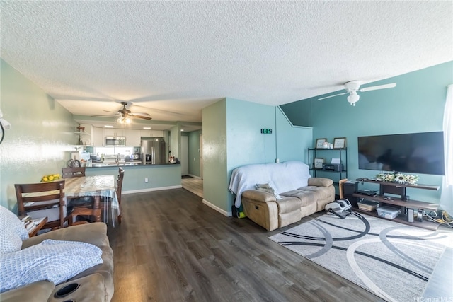living area featuring dark wood-style floors, a textured ceiling, ceiling fan, and baseboards