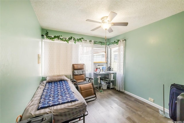 bedroom with a textured ceiling, wood finished floors, a ceiling fan, and baseboards
