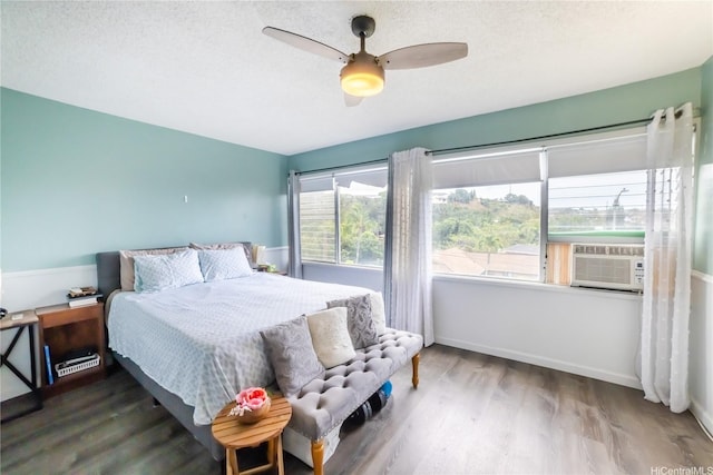 bedroom featuring baseboards, cooling unit, wood finished floors, and ceiling fan