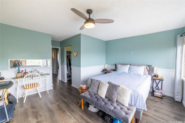 bedroom with a walk in closet, wood finished floors, a ceiling fan, and a closet