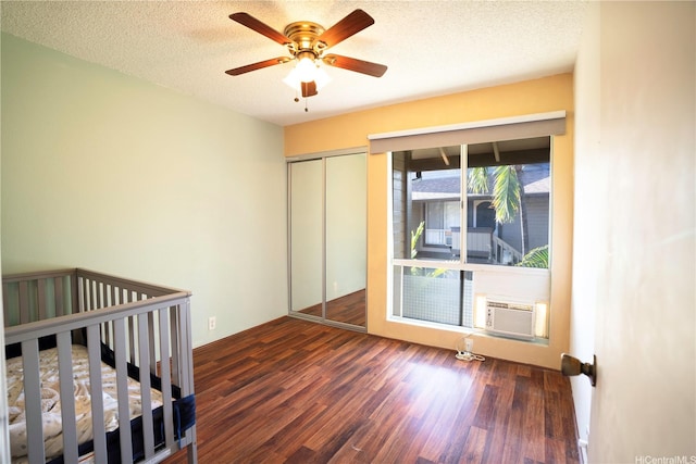 unfurnished bedroom with wood finished floors, a closet, cooling unit, a textured ceiling, and ceiling fan
