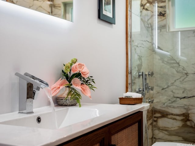 bathroom with a marble finish shower and vanity