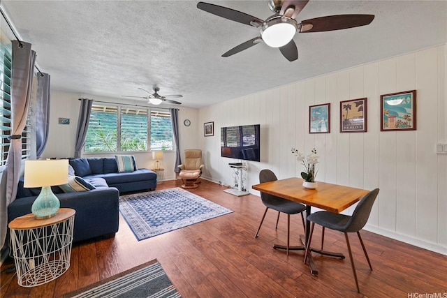 living room featuring wood finished floors, a textured ceiling, a ceiling fan, and baseboards