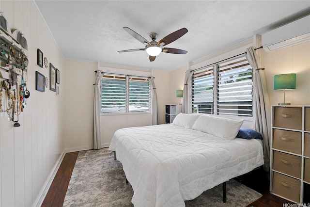 bedroom with baseboards, a ceiling fan, an AC wall unit, and dark wood-style flooring
