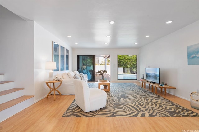 living room featuring stairway, baseboards, wood finished floors, and recessed lighting