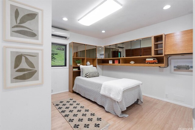 bedroom featuring an AC wall unit, baseboards, wood finished floors, and recessed lighting
