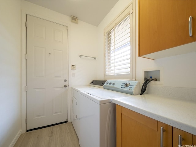 laundry area with washer and dryer, light wood-style floors, and cabinet space