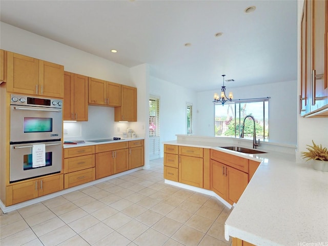 kitchen with a peninsula, a sink, black electric stovetop, light countertops, and double oven