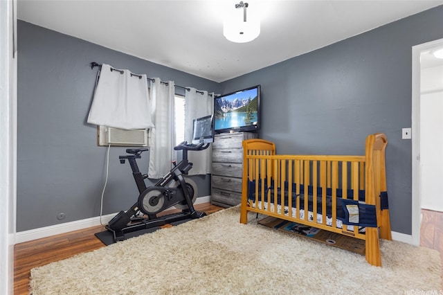 bedroom with baseboards, cooling unit, and wood finished floors