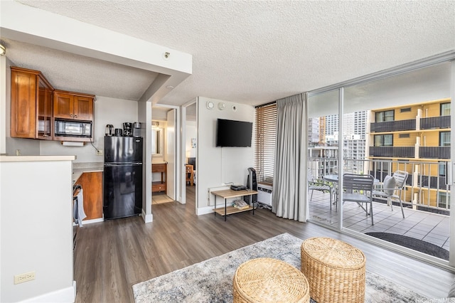 living room featuring baseboards, wood finished floors, a textured ceiling, and expansive windows