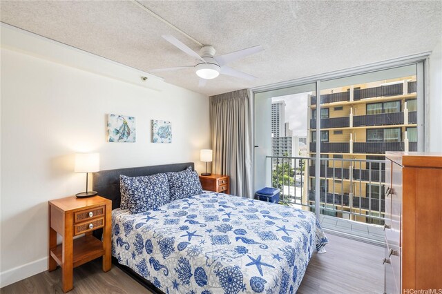bedroom featuring a textured ceiling, baseboards, a wall of windows, wood finished floors, and a ceiling fan