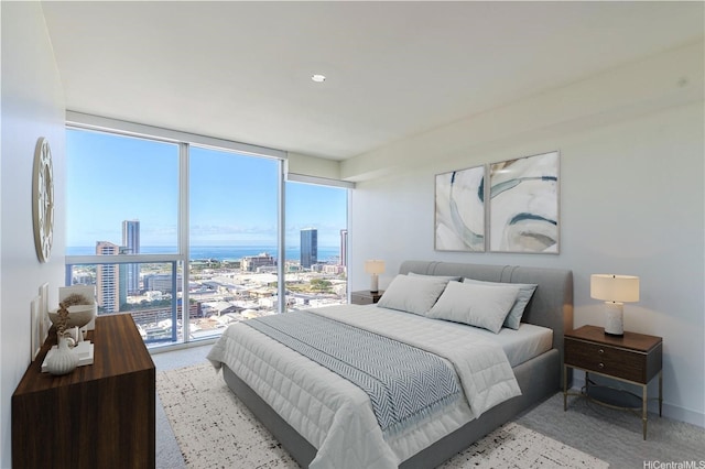 bedroom featuring light colored carpet, expansive windows, and a view of city